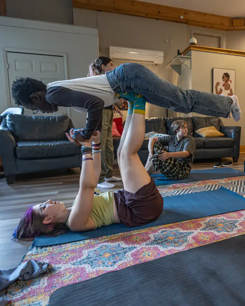 Students performing a partner yoga balance during group therapy at Lake House Academy therapeutic boarding school.