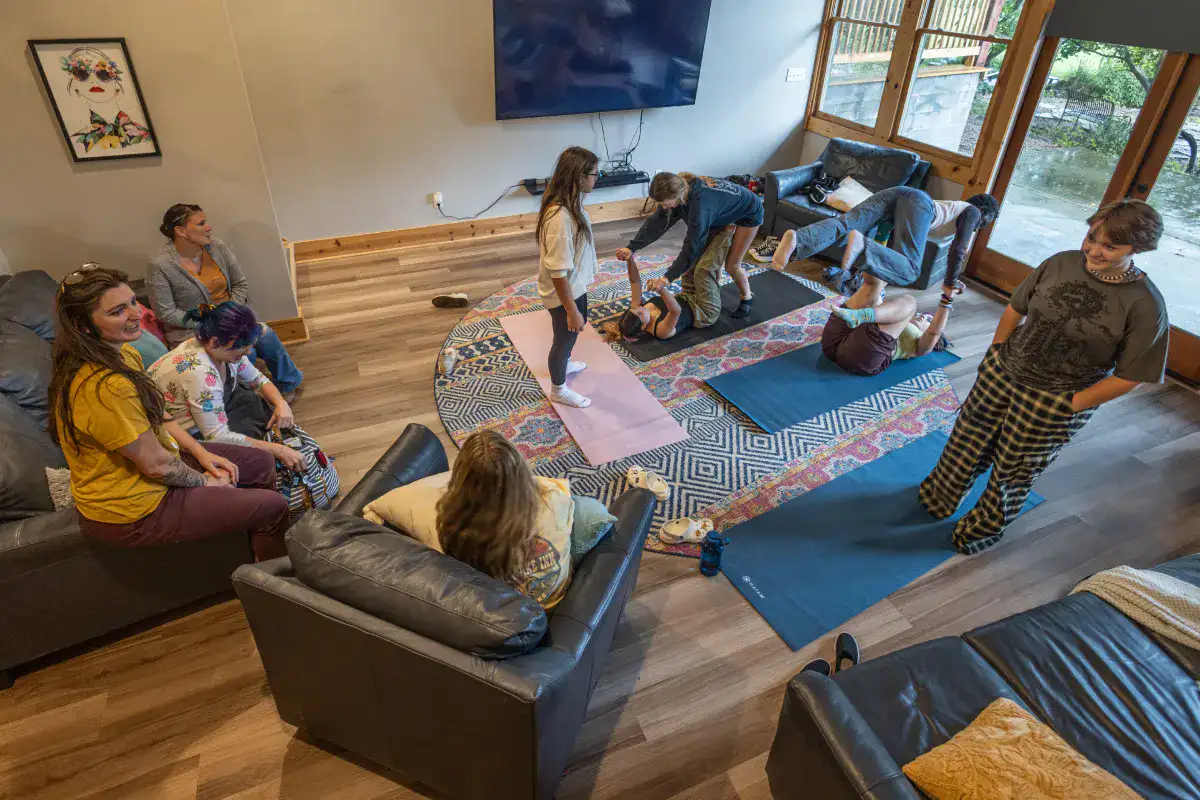 A group of students who practice family systems therapy doing yoga and sitting together in a large room.